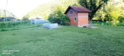 a small house in a yard next to a body of water at Faris in Bihać