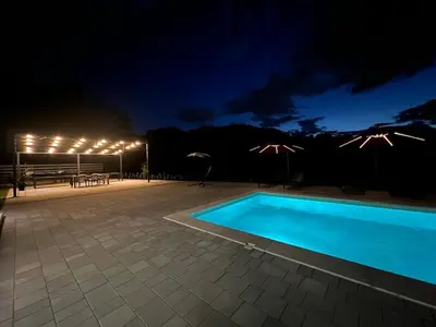 a swimming pool at night with lights on a patio at La Casa di Anna in Slatina Varoš