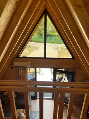 a window in a wooden cabin with a view of a tennis court at Vila Jezero-Jajce in Jezero