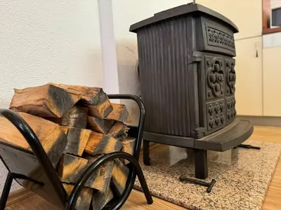 a wood stove sitting next to a chair with a pile of wood at Kuća za odmor- Fojnica in Tješilo