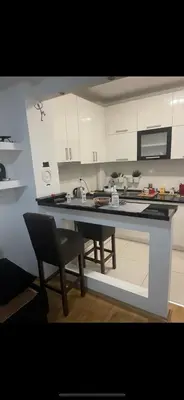 a kitchen with white cabinets and a table and a chair at Apartmani LUX Tamara in Banja Luka