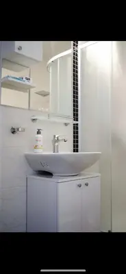 a white bathroom with a sink and a mirror at Apartmani LUX Tamara in Banja Luka