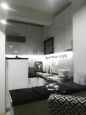 a kitchen with white cabinets and a black counter top at Apartmani LUX Tamara in Banja Luka