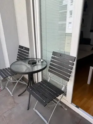 a glass table and two chairs on a balcony at Apartmani LUX Tamara in Banja Luka