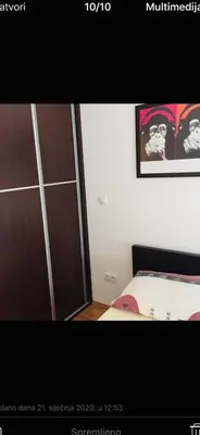 a bedroom with a bed and a cabinet and a picture at Apartmani LUX Tamara in Banja Luka