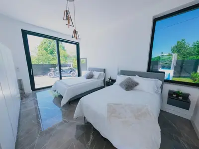 a bedroom with two beds and a large window at Vila Salkic in Cazin