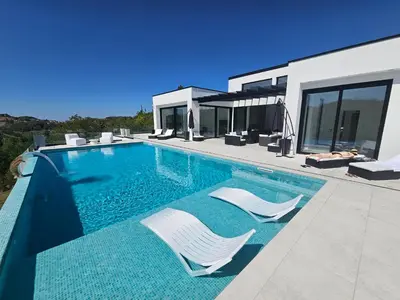 a swimming pool with two chairs and a house at Vila Salkic in Cazin