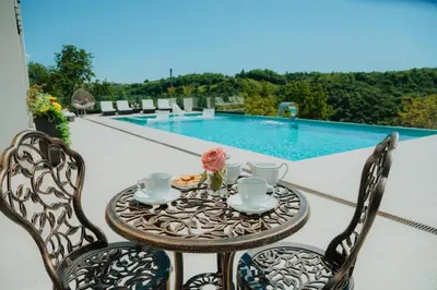 a table and two chairs on a patio with a pool at Vila Salkic in Cazin