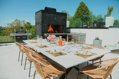 a table with chairs and a fireplace on a patio at Vila Salkic in Cazin