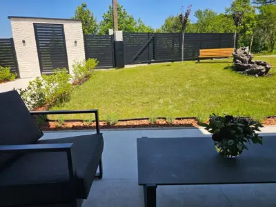 a patio with a table and a bench and grass at Vila Salkic in Cazin