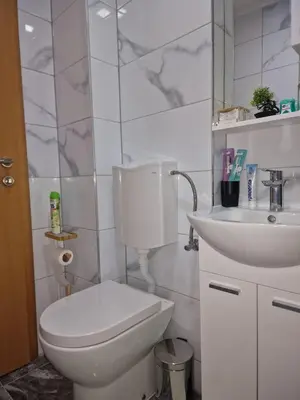 a white bathroom with a toilet and a sink at Apartman Katić in Odžak