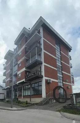 a tall brick building with balconies on a street at Apartman Katić in Odžak