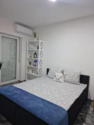 a bedroom with a bed with blue and white sheets at Apartman Katić in Odžak