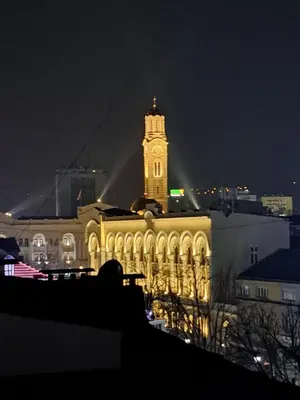 a lit up building with a clock tower at night at Theatre View Banja Luka in Banja Luka