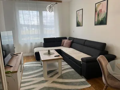 a living room with a black couch and a table at Apartman Delta in Banja Luka