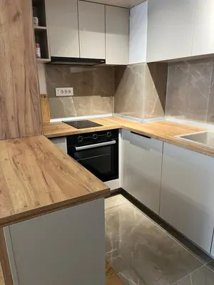 a kitchen with white cabinets and a black stove at Apartman Delta in Banja Luka