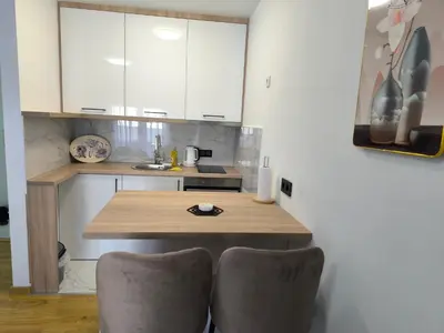 a kitchen with a wooden table and two chairs at Apartman Vanja in Doboj