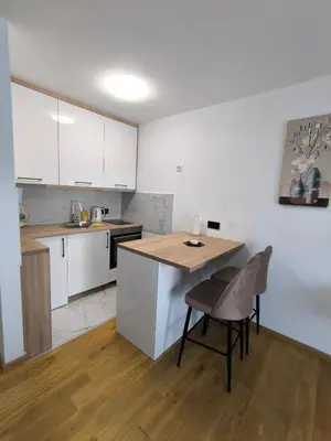 a kitchen with white cabinets and a wooden table and chairs at Apartman Vanja in Doboj