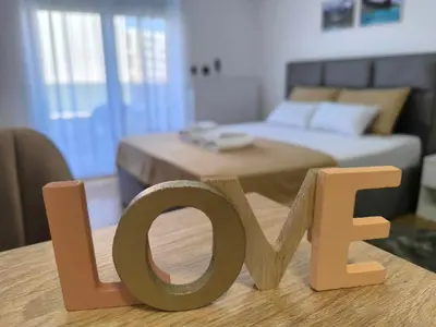a wooden sign that says love on a table in a bedroom at Apartman Vanja in Doboj
