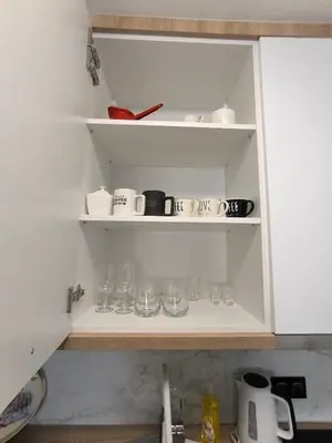 a kitchen shelf with cups and glasses on it at Apartman Vanja in Doboj