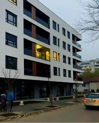 a white building with a car parked in front of it at Stan na dan Banja luka Mejdan in Hiseti