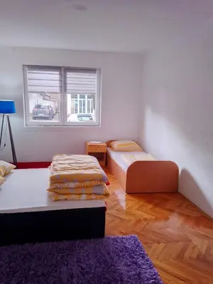 a living room with two beds and a window at Apartmani Amina in Bihać