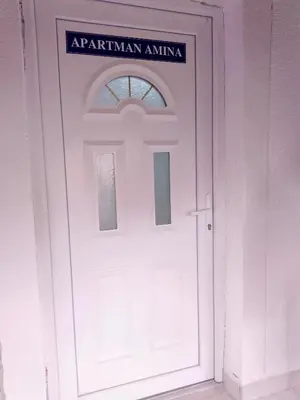 a white door with a sign on top of it at Apartmani Amina in Bihać
