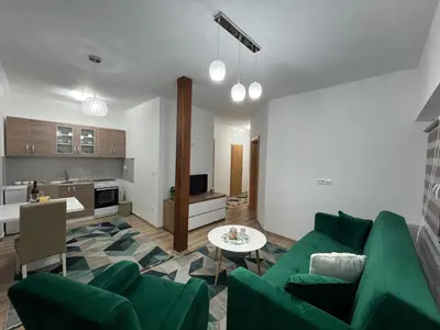 a living room with a green couch and a kitchen at Apartman Mrša in Livno