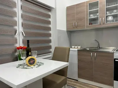 a kitchen with a table with wine bottles and flowers at Apartman Mrša in Livno