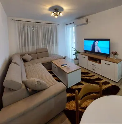 a living room with a couch and a flat screen tv at Apartman Aurora in Modriča