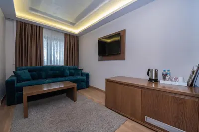 a living room with a blue couch and a tv at Hotel Park in Srebrenik
