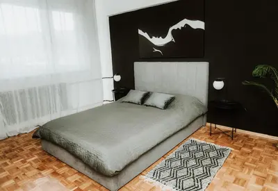 a bedroom with a bed and a black wall at Apartman at 8th in Banja Luka