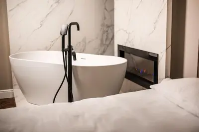 a white bath tub in a bedroom with a fireplace at Ideal Apartments in Banja Luka