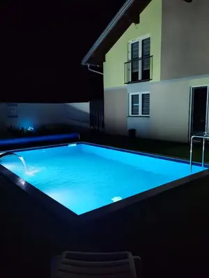 a swimming pool at night with a house in the background at Halal Holidey Kuća za odmor in Spahići