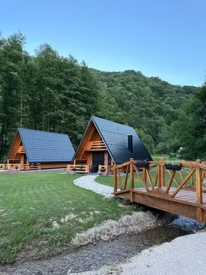 a couple of log homes with a bridge and trees at Plivska vila 2 in Jajce