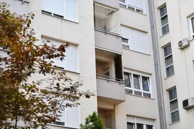 an apartment building with white windows and a tree at Apartman Atrium Banja Luka in Banja Luka