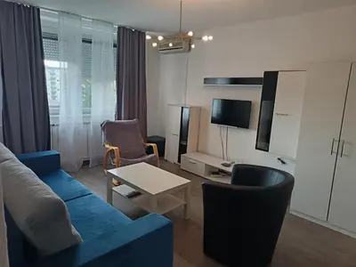 a living room with a blue couch and chairs at City apartmant in Tuzla