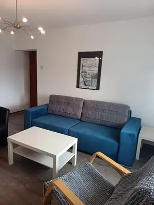 a living room with a blue couch and a table at City apartmant in Tuzla