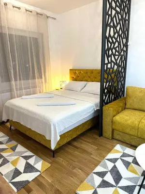 a bedroom with a bed and a yellow chair at Apartman Most in Bosanska Gradiška
