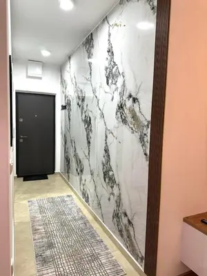 a hallway with a marble wall with a black door at Apartman Most in Bosanska Gradiška