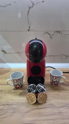 a red coffee maker with two cups and some cookies at Apartman Most in Bosanska Gradiška