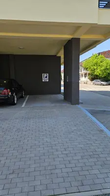 a parking lot with a car parked under a building at Apartman Most in Bosanska Gradiška