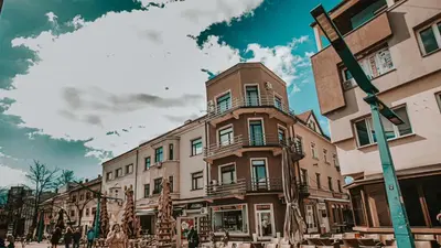 a building on a street with people walking in front of it at Apartman Eden Bihać in Bihać