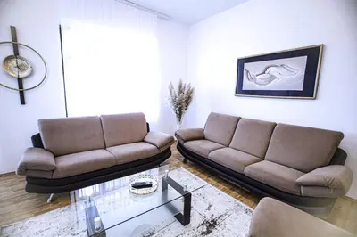 a living room with two couches and a glass table at Apartman Eden Bihać in Bihać