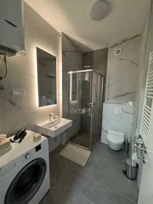 a bathroom with a shower sink and a washing machine at Apartman AK IX in Banja Luka