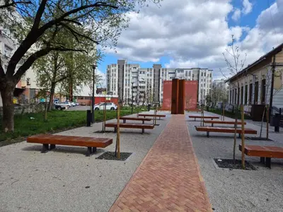 a row of benches in a park with buildings at Apartman Bosiljak in Banja Luka