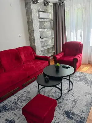 a living room with a red couch and a table at Apartman Bosiljak in Banja Luka