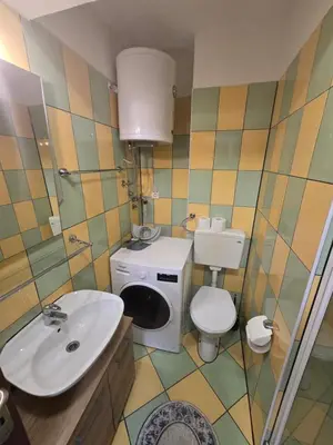 a bathroom with a sink and a toilet and a washing machine at Apartman Sanus in Sanski most