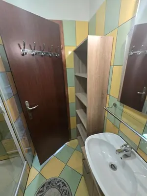 a bathroom with a sink and a wooden door at Apartman Sanus in Sanski most