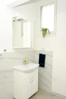 a white bathroom with a sink and a mirror at Apartman Leo Jajce in Jajce